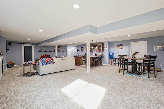 carpeted living room featuring bar and a barn door