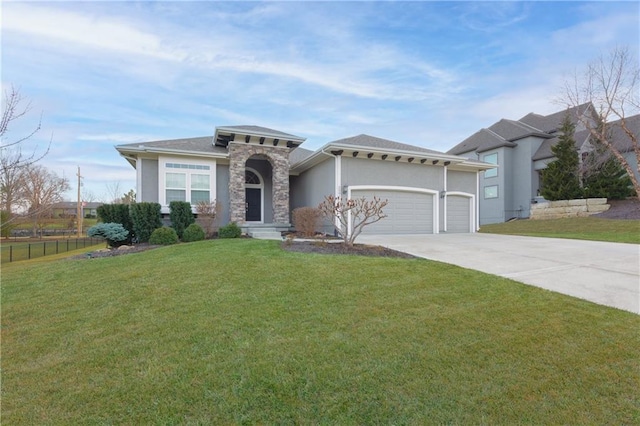 prairie-style home featuring a garage, fence, driveway, stucco siding, and a front yard