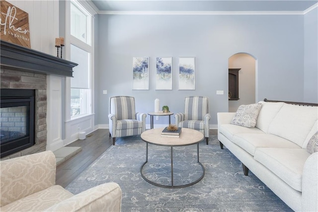 living area with a fireplace, crown molding, baseboards, and wood finished floors