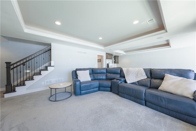 carpeted living room featuring a tray ceiling, visible vents, and stairs