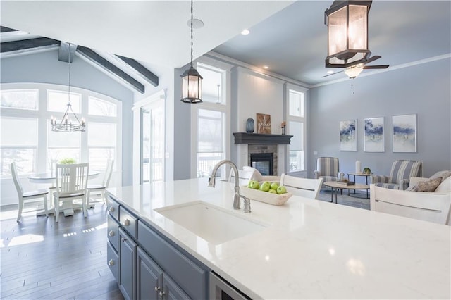 kitchen with crown molding, open floor plan, a fireplace, and a sink