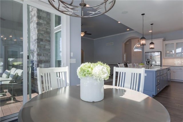 dining space featuring visible vents, arched walkways, dark wood-style floors, ceiling fan, and crown molding