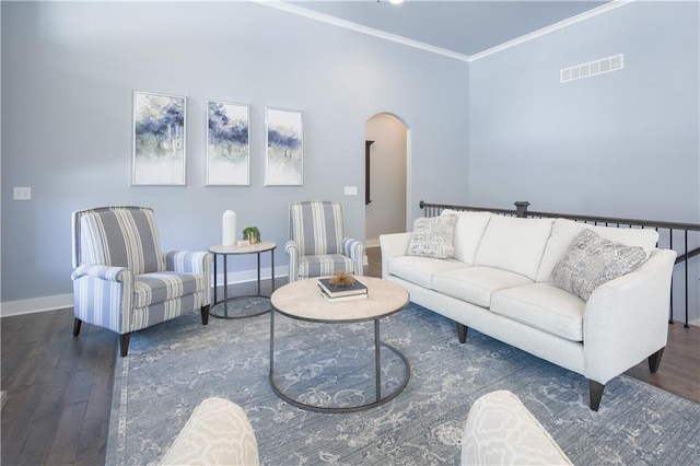 living area featuring baseboards, visible vents, arched walkways, ornamental molding, and wood finished floors