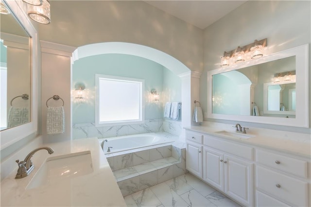 bathroom with marble finish floor, vanity, and a bath