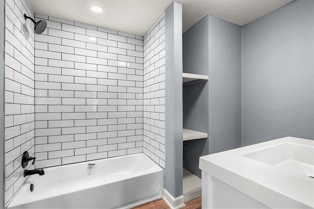 bathroom with tiled shower / bath, wood-type flooring, and sink