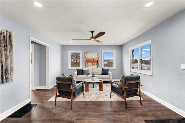 living room featuring dark wood-type flooring and ceiling fan