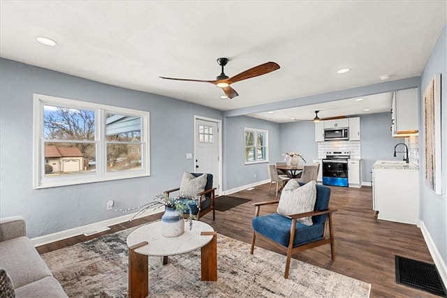 living room featuring ceiling fan, sink, and dark hardwood / wood-style floors