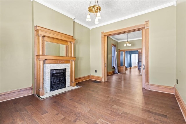 unfurnished living room featuring an inviting chandelier, ornamental molding, a tiled fireplace, and hardwood / wood-style flooring