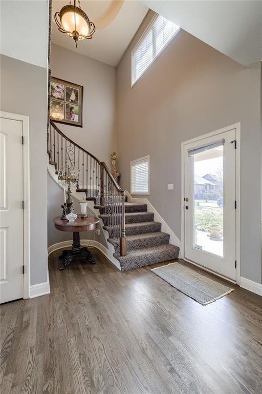 foyer entrance with wood finished floors, baseboards, a high ceiling, and stairs