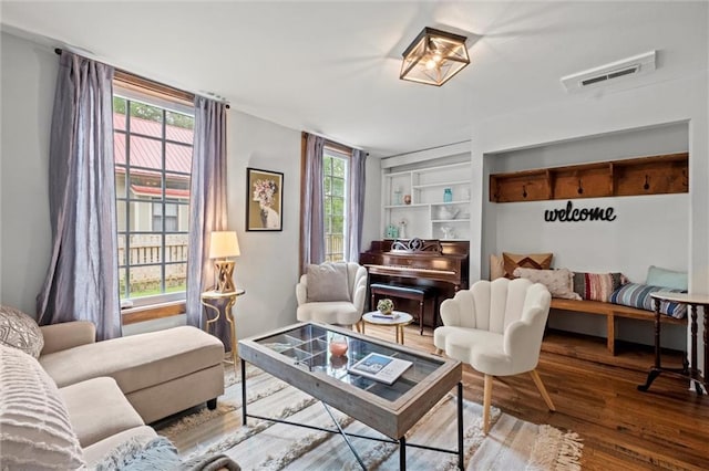 living room with hardwood / wood-style flooring, built in shelves, and a wealth of natural light