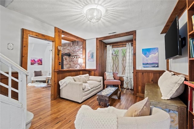 living room with hardwood / wood-style flooring, wooden walls, and a textured ceiling