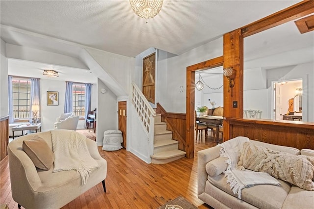 living room with a notable chandelier, light hardwood / wood-style flooring, and a textured ceiling