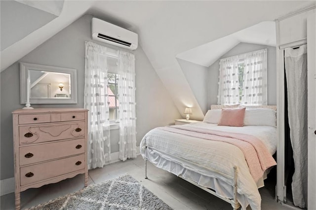 bedroom with lofted ceiling and a wall unit AC