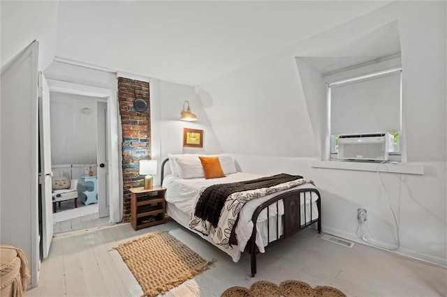 bedroom featuring cooling unit, lofted ceiling, and light wood-type flooring