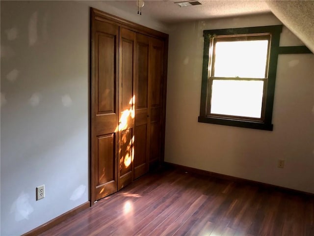 unfurnished bedroom with dark wood-type flooring and a textured ceiling