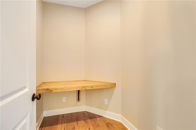 interior space with built in study area, baseboards, and wood finished floors