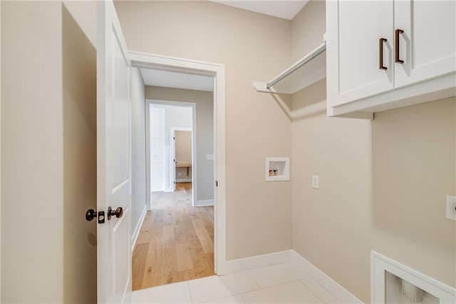 washroom with light wood finished floors, baseboards, hookup for a washing machine, and cabinet space