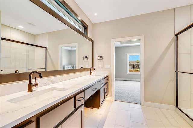 full bath featuring baseboards, a sink, double vanity, and tiled shower