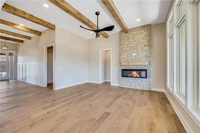unfurnished living room featuring beamed ceiling, light wood-style flooring, a fireplace, and ceiling fan