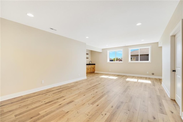 unfurnished living room with light wood finished floors, baseboards, recessed lighting, and visible vents