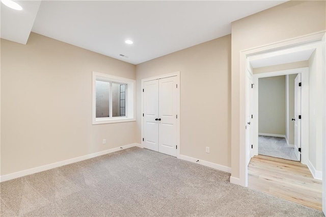 unfurnished bedroom with a closet, light colored carpet, baseboards, visible vents, and recessed lighting