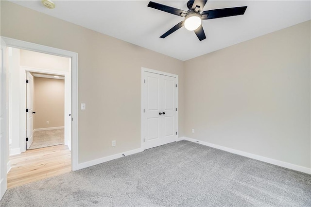 unfurnished bedroom featuring baseboards, a closet, light colored carpet, and ceiling fan