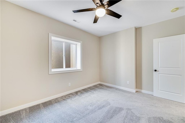 carpeted spare room featuring ceiling fan, baseboards, and visible vents