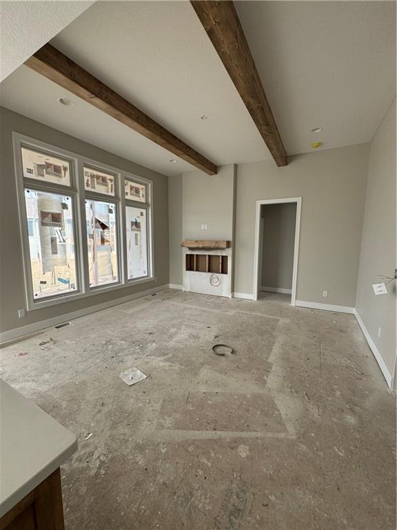 unfurnished living room with beam ceiling