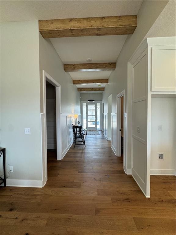 corridor with dark wood-style floors, baseboards, and beam ceiling