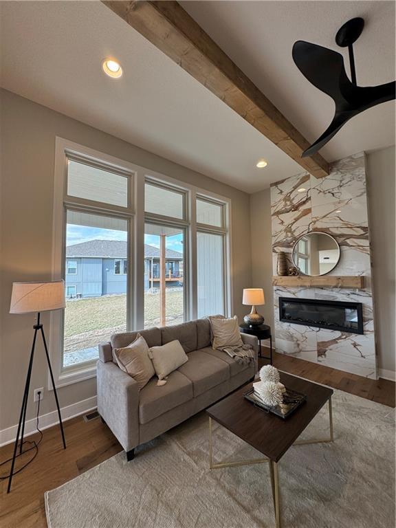 living room featuring a high end fireplace, recessed lighting, baseboards, and wood finished floors