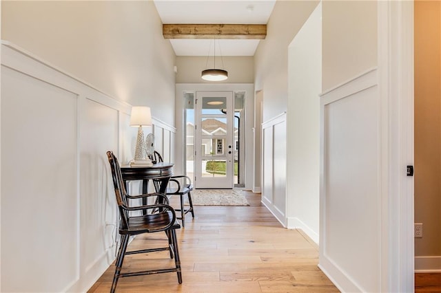 corridor featuring beamed ceiling, light wood-style flooring, and a high ceiling