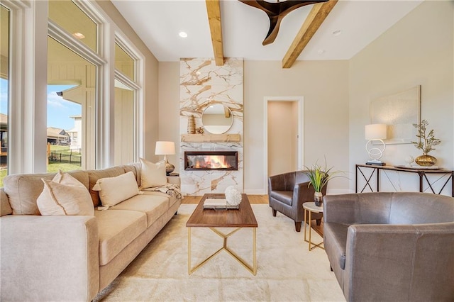 living room featuring a high end fireplace, baseboards, beam ceiling, and light wood-style floors