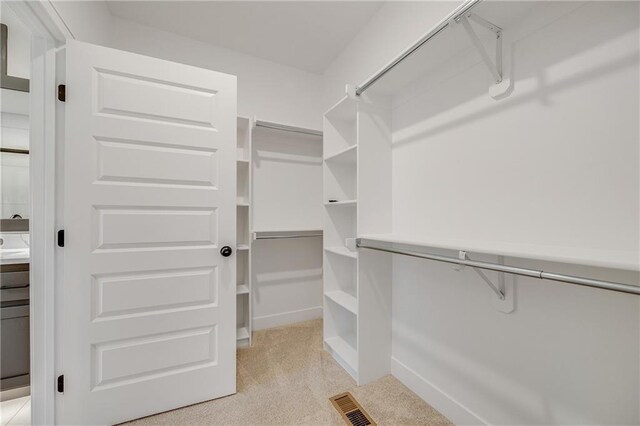 spacious closet featuring light colored carpet and visible vents