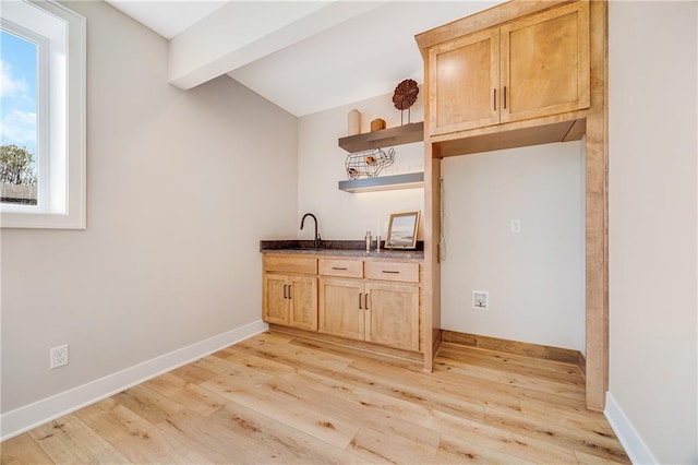 kitchen featuring dark countertops, open shelves, light brown cabinetry, light wood-style flooring, and lofted ceiling