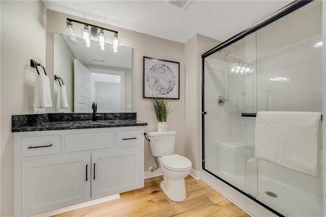 full bathroom with toilet, visible vents, wood finished floors, a shower stall, and vanity