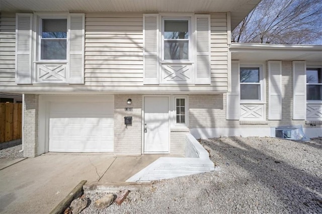 entrance to property with an attached garage, brick siding, and driveway