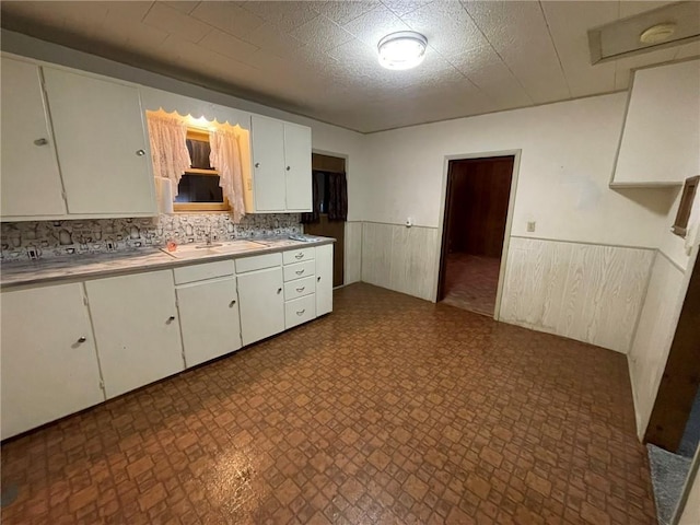 kitchen with sink, white cabinets, and wood walls