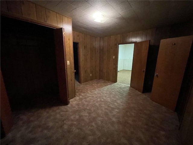 interior space featuring wooden walls and dark carpet