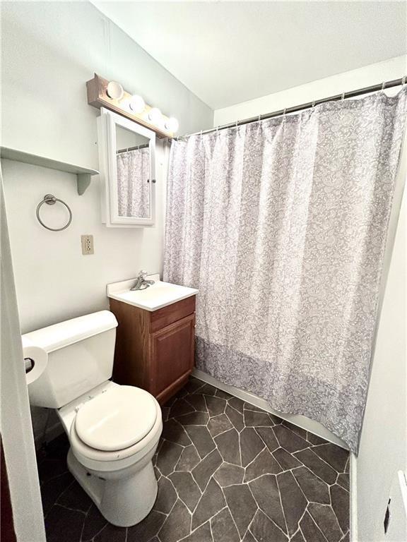 bathroom with vanity, curtained shower, and toilet