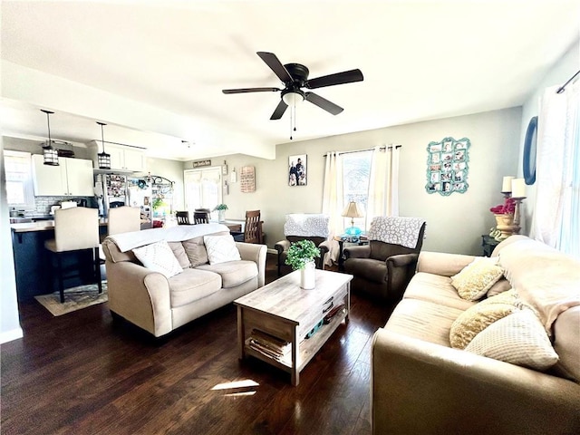 living room featuring dark wood-type flooring, ceiling fan, and plenty of natural light