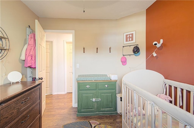 bedroom featuring a nursery area and dark hardwood / wood-style flooring