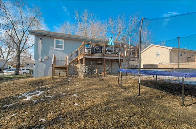 back of property with a deck and a trampoline