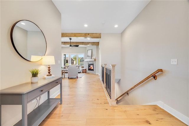 corridor with recessed lighting, beam ceiling, light wood finished floors, and an upstairs landing