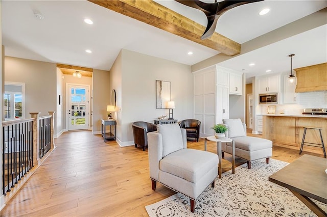 living area featuring baseboards, beam ceiling, light wood-style floors, and recessed lighting