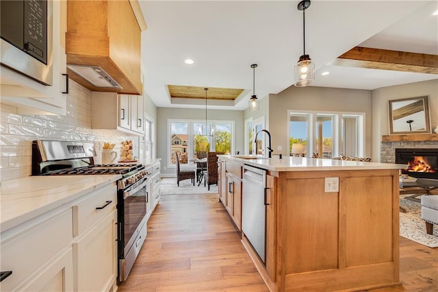 kitchen featuring recessed lighting, stainless steel appliances, a raised ceiling, decorative backsplash, and light wood-style flooring