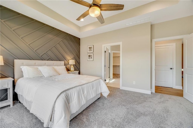 bedroom featuring a tray ceiling, visible vents, a ceiling fan, baseboards, and light colored carpet