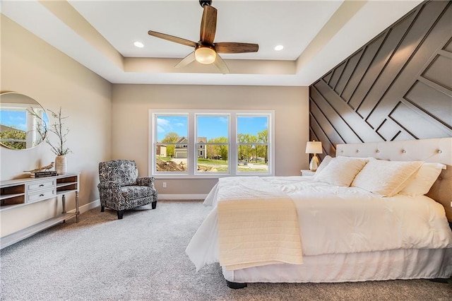 bedroom featuring baseboards, carpet flooring, a raised ceiling, and multiple windows