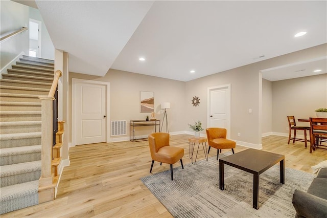 living area featuring baseboards, stairs, visible vents, and light wood-type flooring