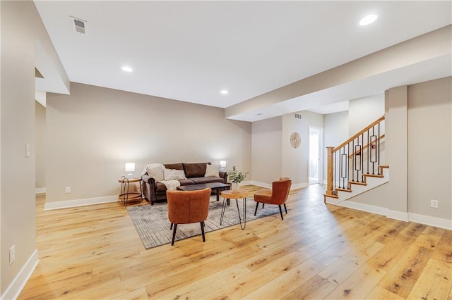 living area featuring light wood-type flooring, baseboards, visible vents, recessed lighting, and stairs