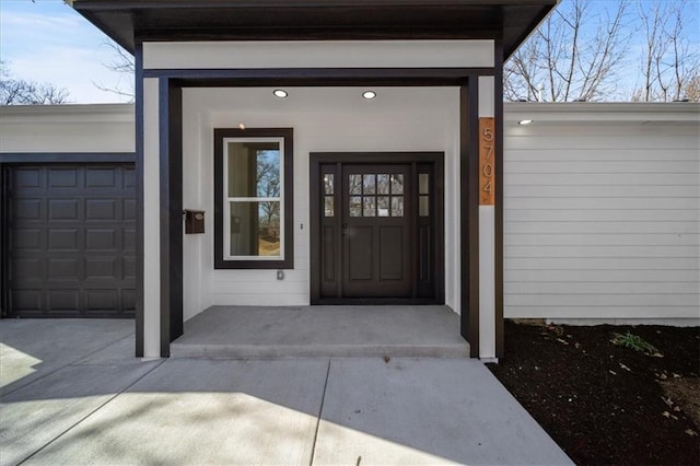 doorway to property featuring an attached garage and concrete driveway